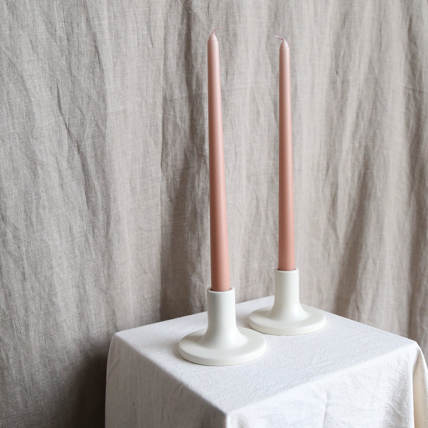 Pair of peach taper candles in white holders available at Rook & Rose.
